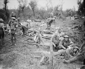 THE BATTLE OF PASSCHENDAELE, JULY-NOVEMBER 1917 Battle of Pilckem Ridge. Wounded men are tended by medical staff as they lie on stretchers on the grass at an RAMC advanced dressing station near Boesinghe (on the left flank of the British Fifth Army). One man has his arm in a sling. 31 July 1917 Battle of Pilckem Ridge. Wounded men are tended by medical staff as they lie on stretchers on the grass at an RAMC advanced dressing station near Boesinghe (on the left flank of the British Fifth Army). One man has his arm in a sling. 31 July 1917. © IWM (Q 5730)
